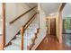 Carpeted staircase with wooden railing leads to the upper level, complemented by hardwood floors and natural light at 130 Floss Flower Ct, Roswell, GA 30076