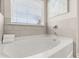 Bathroom featuring a large soaking tub by a window, paired with neutral tile for a serene and spa-like experience at 219 Whispering Pines Ave, Conyers, GA 30094