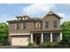Charming two-story brick home with covered porch and attached garage, surrounded by lush landscaping at 219 Whispering Pines Ave, Conyers, GA 30094