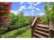 Beautiful backyard featuring wooden steps, a black metal fence, lush greenery, and a colorful tree at 7340 Jamestown Dr, Alpharetta, GA 30005
