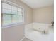Clean bathroom featuring a soaking tub by a window, offering natural light at 3241 Briscoe Rd, Loganville, GA 30052
