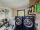 Laundry room with modern washer and dryer, shelving, window, and overhead lighting at 3241 Briscoe Rd, Loganville, GA 30052