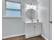 Bathroom featuring a round mirror, white vanity, wood-look tile, and modern lighting at 143 Navajo Trl, Rydal, GA 30171