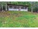 Exterior view of a rustic-style chicken coop with screened windows and a door, set on a lush, green hillside at 143 Navajo Trl, Rydal, GA 30171