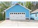 Two-car garage featuring a white door with black hardware and stone accents on a charming blue home at 505 Alta Ct, Villa Rica, GA 30180