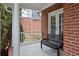 Cozy covered porch with a metal bench, offering a relaxing outdoor space with brick accents at 1692 Holcomb Lake Rd, Marietta, GA 30062