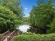 Lush backyard view of the calm lake waters, framed by mature trees and seen from a wooden deck at 940 Kinghorn Nw Dr, Kennesaw, GA 30152