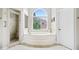 Luxurious bathroom features a soaking tub, separate shower, and a large arched window at 940 Kinghorn Nw Dr, Kennesaw, GA 30152
