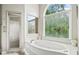 Bright bathroom boasts a soaking tub, walk-in shower, and a large window with green views at 940 Kinghorn Nw Dr, Kennesaw, GA 30152