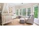 Charming bedroom with a crib, dresser, and sitting chair next to a large window at 940 Kinghorn Nw Dr, Kennesaw, GA 30152