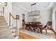 Elegant dining room features a wooden table, upholstered chairs, chandelier, stairs and plantation shutters at 940 Kinghorn Nw Dr, Kennesaw, GA 30152