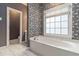Bathroom featuring a soaking tub with a window, decorative wallpaper and neutral tiling at 2651 Briarlake Ne Rd, Atlanta, GA 30345