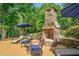 Outdoor stone fireplace with seating area, lush landscaping, and a beautiful backyard setting at 106 Stephens Farm Dr, Canton, GA 30115