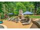Outdoor living area with a stone fireplace, lounge chairs, tables, umbrellas, and a lush green lawn at 106 Stephens Farm Dr, Canton, GA 30115