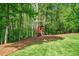 Backyard playhouse with slide and climbing wall, set amidst a backdrop of mature trees and lush greenery at 106 Stephens Farm Dr, Canton, GA 30115