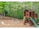 Charming backyard playhouse with slide, climbing wall, and a nearby fire pit, nestled among mature trees at 106 Stephens Farm Dr, Canton, GA 30115