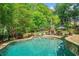 Beautiful backyard pool area with a hot tub, and a stone patio surrounded by mature trees and lush landscaping at 106 Stephens Farm Dr, Canton, GA 30115