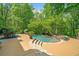 Gorgeous pool area featuring a stone-lined pool, hot tub, slide, mature trees, and an outdoor dining area at 106 Stephens Farm Dr, Canton, GA 30115