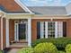 Brick home front entrance with black door, sidelights and white trim and bench at 1435 Harburn Ct, Cumming, GA 30041