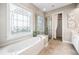 Luxurious main bathroom featuring a jetted tub, glass-enclosed shower, and elegant window at 1435 Harburn Ct, Cumming, GA 30041