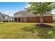 Rear of a brick home with a covered porch, showcasing a well-manicured lawn and mature trees at 2055 Hickory Station Cir, Snellville, GA 30078