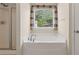 Bright bathroom featuring a garden tub beneath a window and separate glass-enclosed shower at 2055 Hickory Station Cir, Snellville, GA 30078