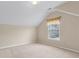 An attic bedroom with a vaulted ceiling featuring a window providing natural light and carpeted flooring at 2055 Hickory Station Cir, Snellville, GA 30078