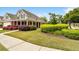 Exterior view showcasing lush lawn, attractive shrubbery, brick facade, and a covered porch lined with columns at 2055 Hickory Station Cir, Snellville, GA 30078
