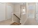 A carpeted hallway with white doors, white walls, a stairway, and a decorative light fixture at 2055 Hickory Station Cir, Snellville, GA 30078