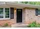 Close-up of a brick house entrance with a black door, black shutters, and natural light at 980 Oakton Sw Dr, Marietta, GA 30060