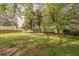 Large, grassy backyard surrounded by mature trees and a wooden fence at 228 Amour Sw Way, Lilburn, GA 30047