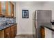 Compact kitchen features stainless steel refrigerator, mosaic backsplash, wood cabinets, and black countertops at 2871 Parkridge Ne, Brookhaven, GA 30319