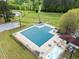 Aerial view of a fenced community pool area surrounded by lush greenery, a playground, and a tennis court at 1911 Rollingwood Se Dr, Atlanta, GA 30316