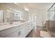 Bright bathroom with double sinks, large mirrors, white cabinetry, and a glass-enclosed shower at 3322 Grace Farm Ln, Buford, GA 30519