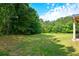 Large private backyard with lush green lawn and mature trees at 6816 Diamond Dr, Rex, GA 30273