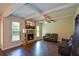 Relaxing living room with a stone fireplace, ceiling fan, hardwood floors, and bright natural light at 6816 Diamond Dr, Rex, GA 30273