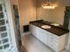 Bathroom featuring sleek white cabinets, dual sinks, dark countertops, and marble tile, blending style and function at 870 Thornberry Dr, Alpharetta, GA 30022