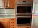 Modern kitchen with stainless steel Wolf double ovens, granite countertops, wood cabinets, tile backsplash, and hardwood floors at 870 Thornberry Dr, Alpharetta, GA 30022