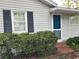 Exterior view highlighting a home's side entrance with a storm door, accented by a dark shuttered window and surrounding greenery at 1311 Sylvan Cir, Brookhaven, GA 30319