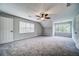 Large bedroom with gray walls, plush carpet, ceiling fan, two windows, and two white doors at 1885 Vintage Dr, Snellville, GA 30078