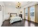 Bright bedroom featuring a large window, stylish chandelier, and dark hardwood floors at 215 Britten Pass, Alpharetta, GA 30009