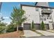 Townhome featuring a two-car garage with brick exterior and manicured landscaping at 215 Britten Pass, Alpharetta, GA 30009