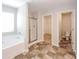 Bright bathroom featuring a soaking tub, separate glass shower, and tile flooring at 89 Citadel Dr, Hampton, GA 30228