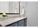 Stylish powder room featuring granite counters, blue cabinets and patterned wallpaper at 125 Windy Pines Pass, Roswell, GA 30075