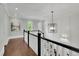 Hallway with white paneled walls, a black and white staircase, and a modern chandelier at 125 Windy Pines Pass, Roswell, GA 30075