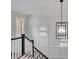 Hallway with white paneled walls, a black and white staircase, and a modern chandelier at 125 Windy Pines Pass, Roswell, GA 30075