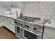 Professional-grade stainless steel gas range and oven with tile backsplash and modern countertops at 125 Windy Pines Pass, Roswell, GA 30075