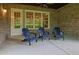 Covered patio with brick walls, ceiling fan, and three blue Adirondack chairs at 125 Windy Pines Pass, Roswell, GA 30075