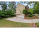 Back of brick home featuring an attached 3 car garage and mature trees at 1720 Greystone Trce, Conyers, GA 30013