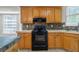 Well-lit kitchen with black appliances, wooden cabinets, and a tiled backsplash at 1720 Greystone Trce, Conyers, GA 30013
